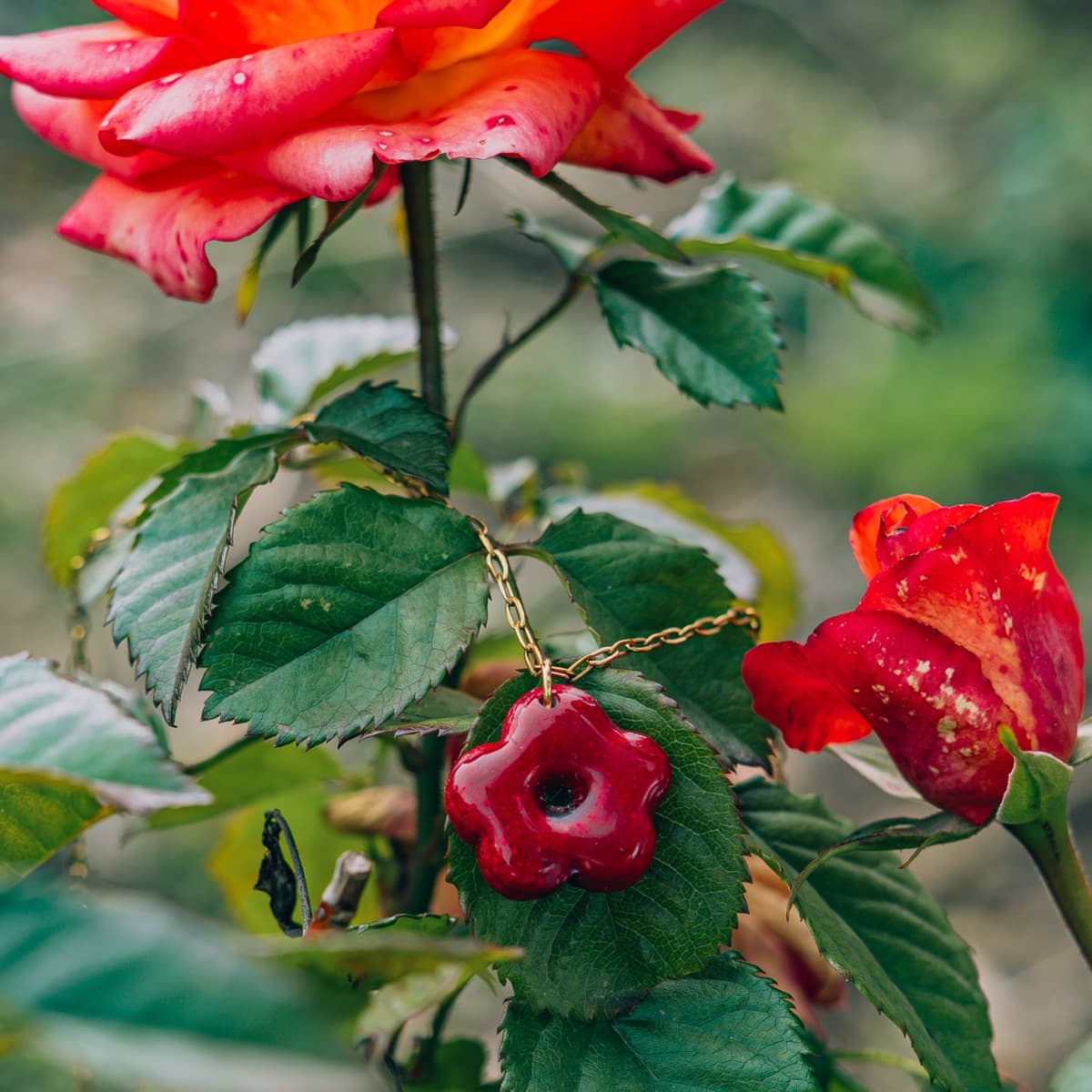 Colgante de flor roja en resina entre rosales reales