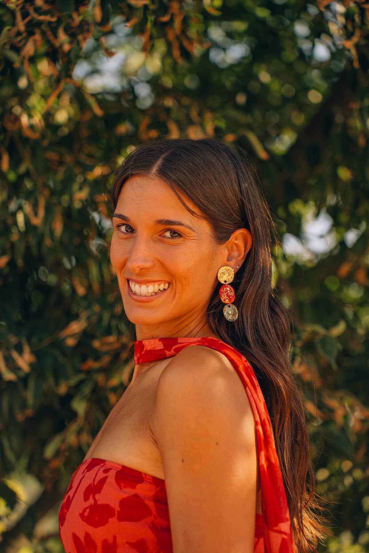 Modelo con vestido rojo y pendientes largos de la Colección Invitada entre olivos